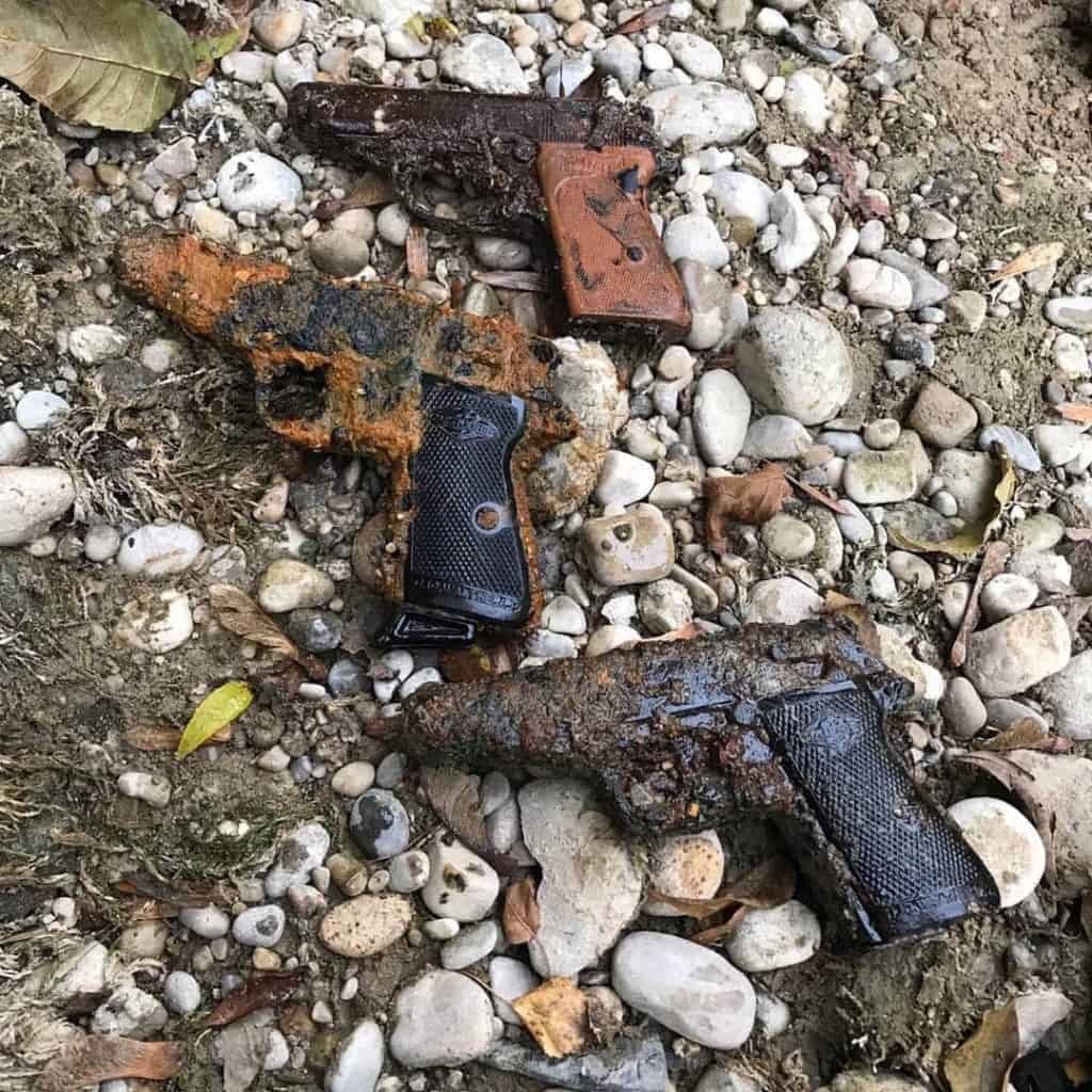 tři zrezivělé pistole položené na kamenech